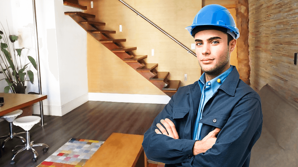 Engenheiro de capacete azul e braços cruzados diante de uma escada de madeira com viga central e corrimão de inox